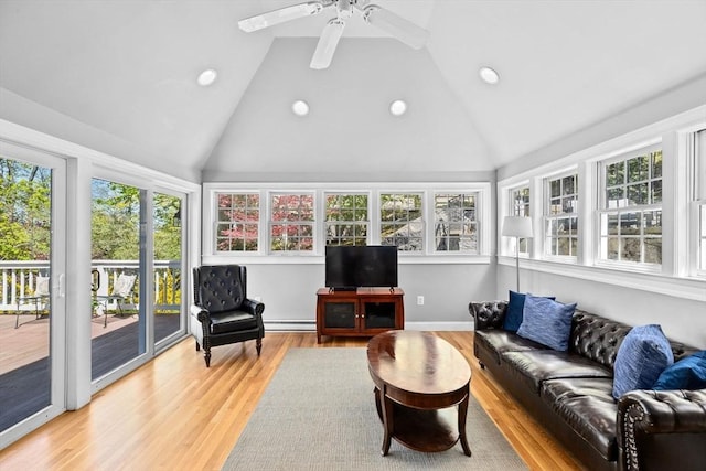 sunroom with vaulted ceiling, plenty of natural light, wood finished floors, and a deck