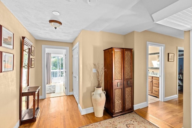 interior space with light wood-type flooring, a sink, and baseboards