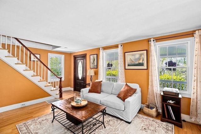 living area featuring baseboards, stairway, and light wood-type flooring