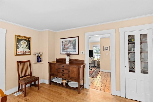 sitting room featuring crown molding, baseboards, visible vents, and light wood-style floors