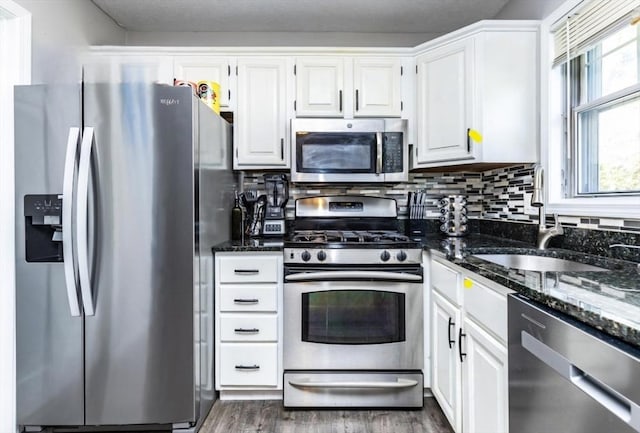 kitchen featuring a sink, dark stone counters, white cabinetry, and stainless steel appliances