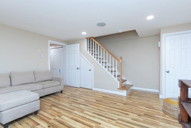 living area featuring baseboards, recessed lighting, light wood-style flooring, and stairs