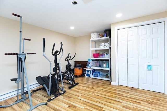exercise room featuring recessed lighting, a baseboard heating unit, and light wood-style floors