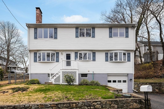 colonial house featuring a garage, fence, a chimney, aphalt driveway, and a front lawn