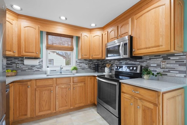 kitchen with backsplash, light countertops, appliances with stainless steel finishes, and a sink