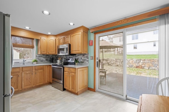 kitchen featuring stainless steel appliances, recessed lighting, a sink, light countertops, and tasteful backsplash