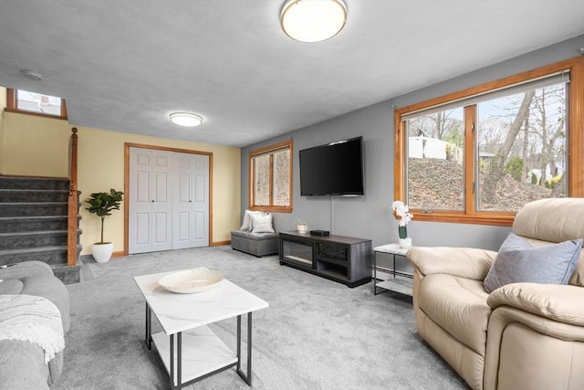 carpeted living area featuring stairs, baseboards, and a healthy amount of sunlight