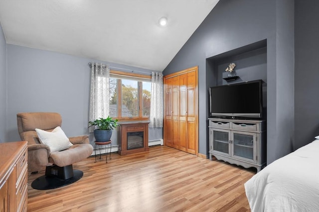 bedroom featuring lofted ceiling, light wood-type flooring, and baseboard heating
