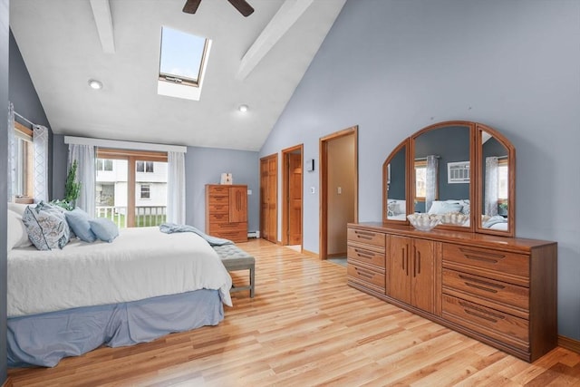 bedroom with a skylight, high vaulted ceiling, an AC wall unit, a ceiling fan, and light wood-style floors