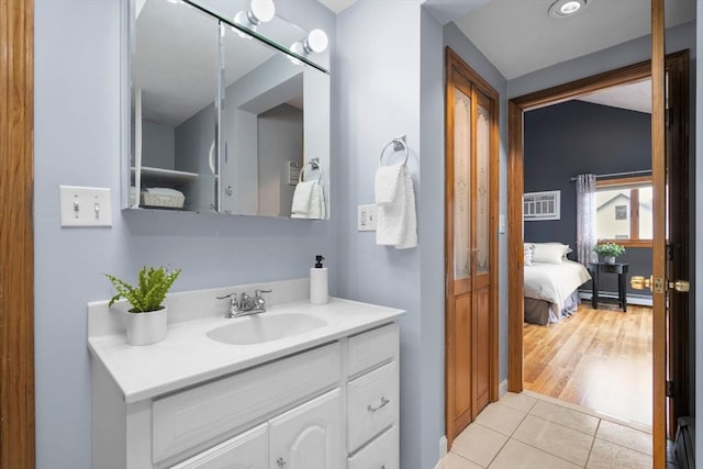 ensuite bathroom with a baseboard heating unit, tile patterned flooring, ensuite bath, and vanity