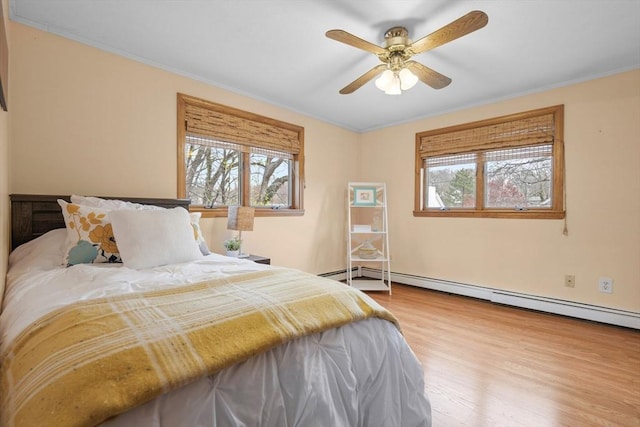 bedroom featuring crown molding, a ceiling fan, baseboard heating, and wood finished floors