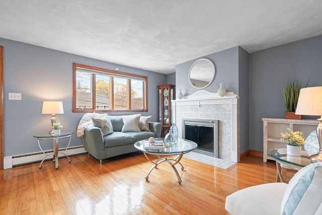 living room with a fireplace, wood finished floors, baseboards, and a baseboard heating unit
