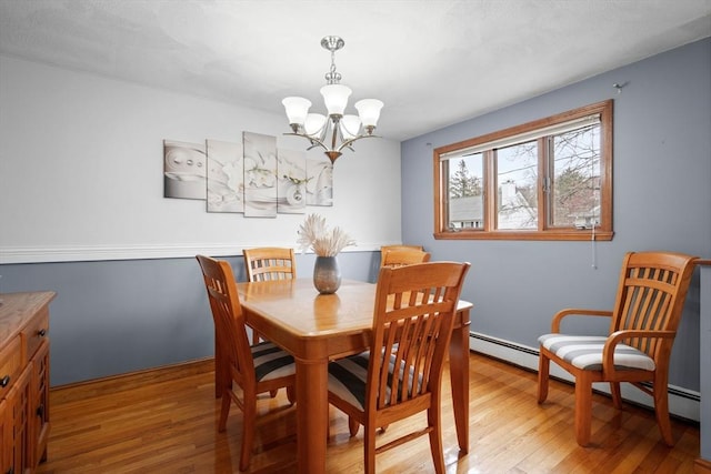 dining room with light wood-style floors, baseboard heating, and an inviting chandelier
