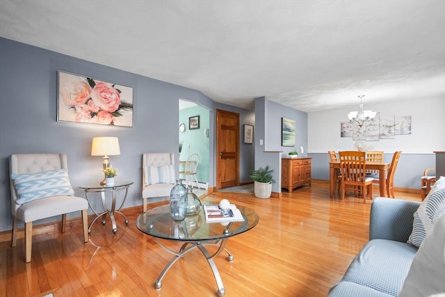 living area featuring a baseboard radiator, a notable chandelier, baseboards, and light wood-style floors