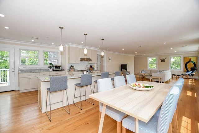 dining area with crown molding, sink, and light wood-type flooring