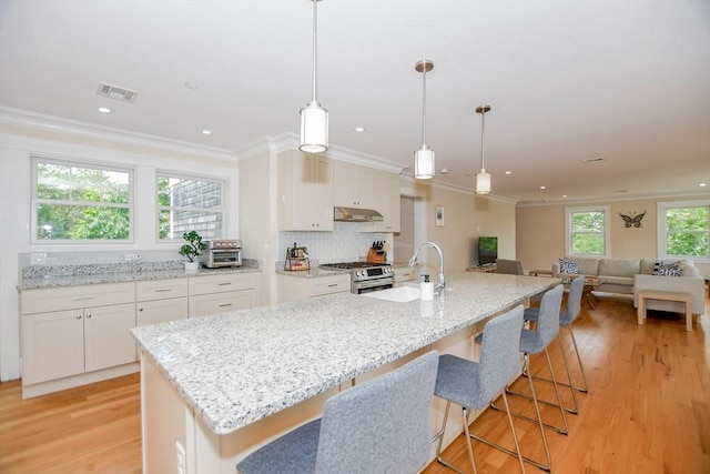 kitchen featuring white cabinetry, a large island, decorative light fixtures, and stainless steel gas stove