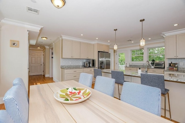 dining area with crown molding, sink, and light hardwood / wood-style flooring