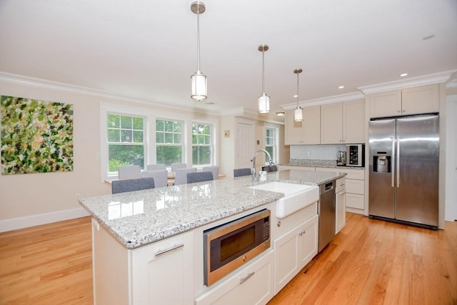 kitchen with sink, crown molding, hanging light fixtures, stainless steel appliances, and a center island with sink