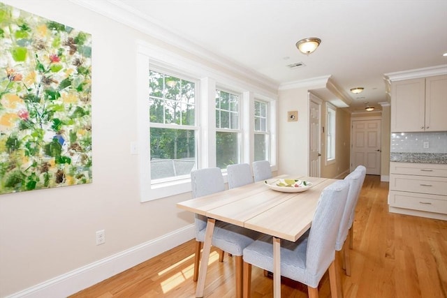 dining room with ornamental molding and light wood-type flooring