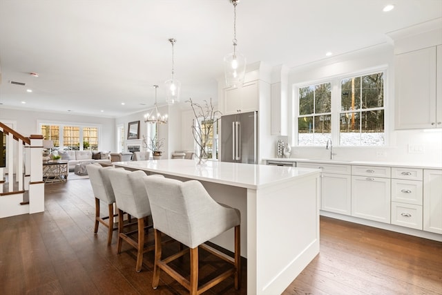 kitchen featuring white cabinets, dark hardwood / wood-style flooring, high end refrigerator, and a kitchen island