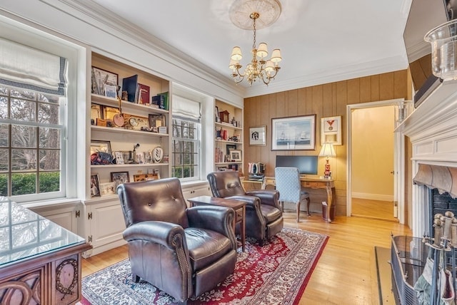 living area with a notable chandelier, crown molding, built in shelves, and light hardwood / wood-style flooring