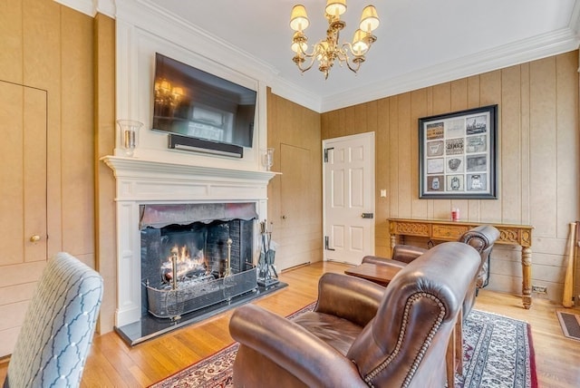 living room with crown molding, light wood-type flooring, wood walls, and a chandelier