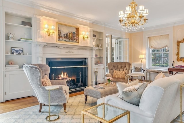 sitting room with built in shelves, ornamental molding, a chandelier, and light hardwood / wood-style floors