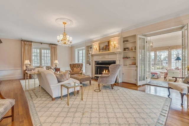 living room featuring crown molding, a chandelier, light hardwood / wood-style floors, and a healthy amount of sunlight