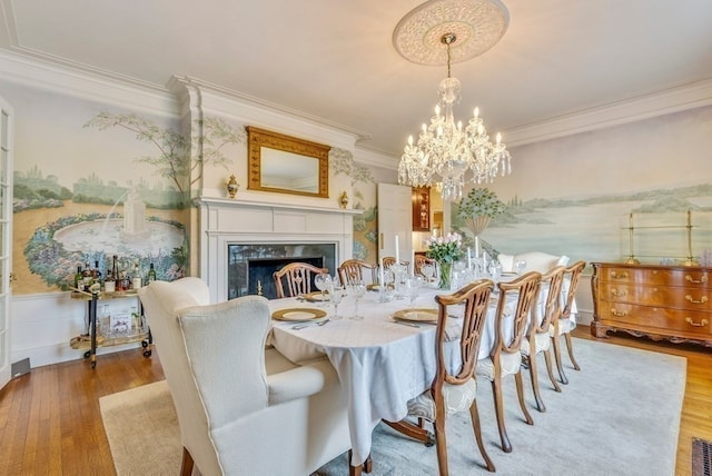 dining area with a notable chandelier, ornamental molding, light hardwood / wood-style flooring, and a fireplace