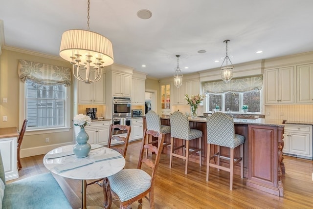 dining space featuring light hardwood / wood-style flooring, crown molding, and a notable chandelier