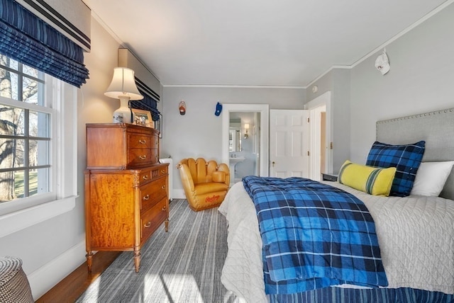 bedroom with connected bathroom, dark hardwood / wood-style flooring, and ornamental molding