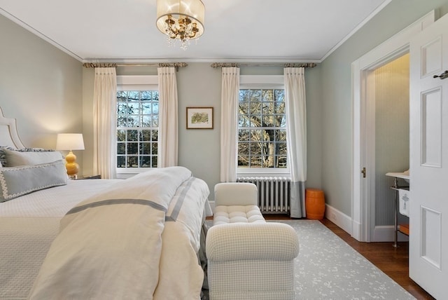 bedroom with a notable chandelier, dark wood-type flooring, ornamental molding, and radiator heating unit