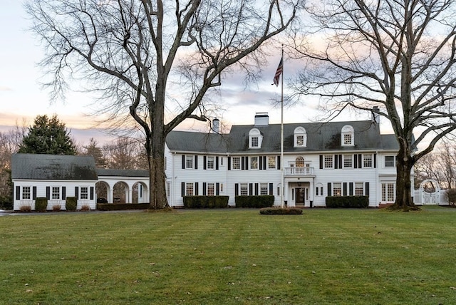 view of front of house featuring a balcony and a yard