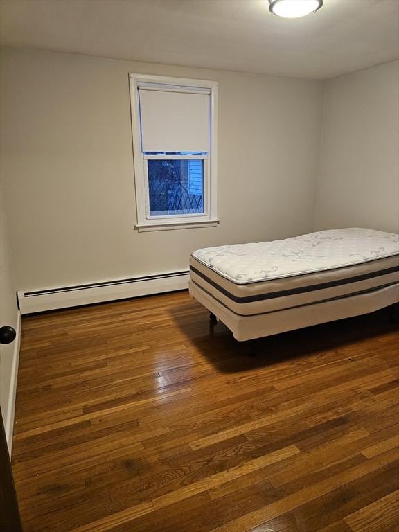 unfurnished bedroom featuring baseboard heating and dark wood-type flooring