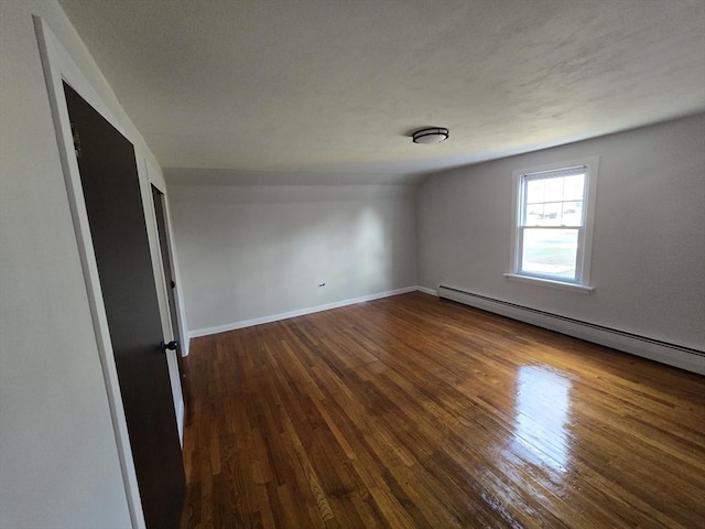 interior space featuring lofted ceiling, dark wood-type flooring, and a baseboard heating unit