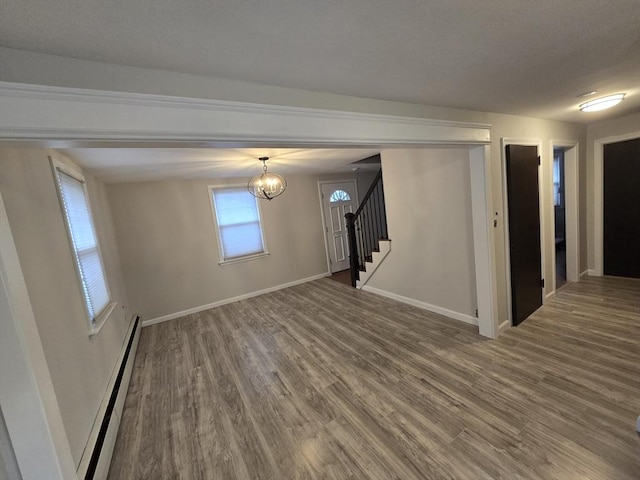 unfurnished room featuring wood-type flooring, a baseboard radiator, and a notable chandelier