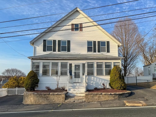 american foursquare style home featuring entry steps, fence, and roof with shingles