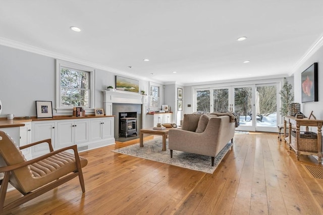 living room featuring crown molding, light wood-style flooring, and a wealth of natural light