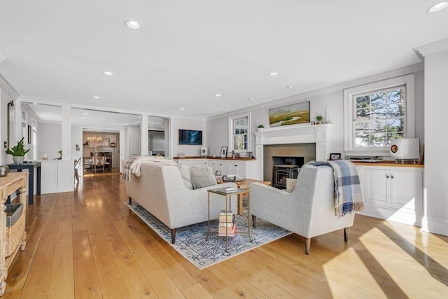 living area featuring recessed lighting, light wood-style flooring, and crown molding