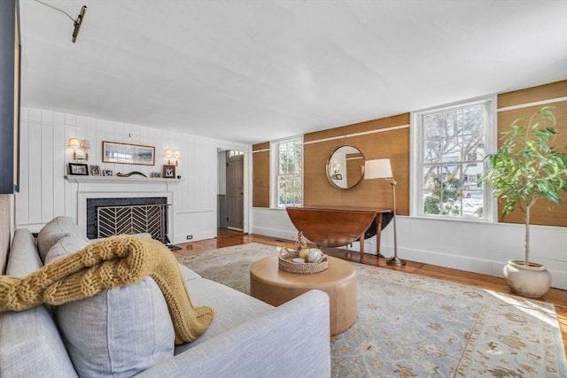 living room featuring baseboards, plenty of natural light, wood finished floors, and a fireplace