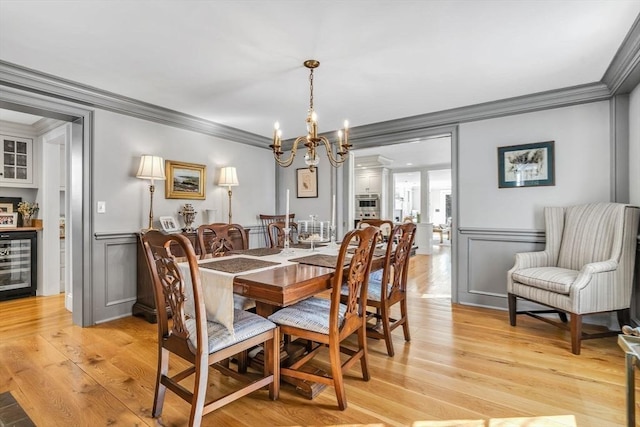 dining area with light wood-style flooring, a wainscoted wall, beverage cooler, and crown molding