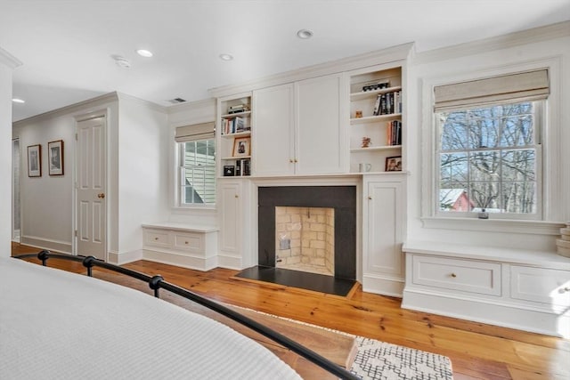 bedroom with a fireplace with flush hearth, ornamental molding, wood finished floors, recessed lighting, and baseboards