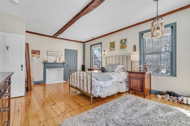 bedroom featuring beamed ceiling, multiple windows, crown molding, and light wood-style floors