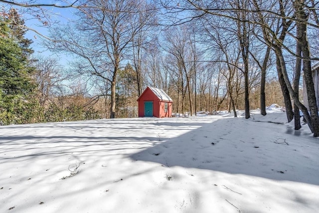 yard layered in snow featuring an outbuilding and a storage unit