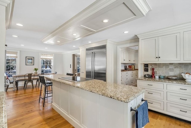 kitchen with a kitchen island, stainless steel built in fridge, white cabinets, crown molding, and black electric stovetop