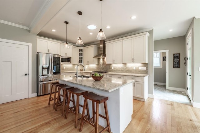 kitchen featuring crown molding, a breakfast bar, wall chimney range hood, a sink, and appliances with stainless steel finishes