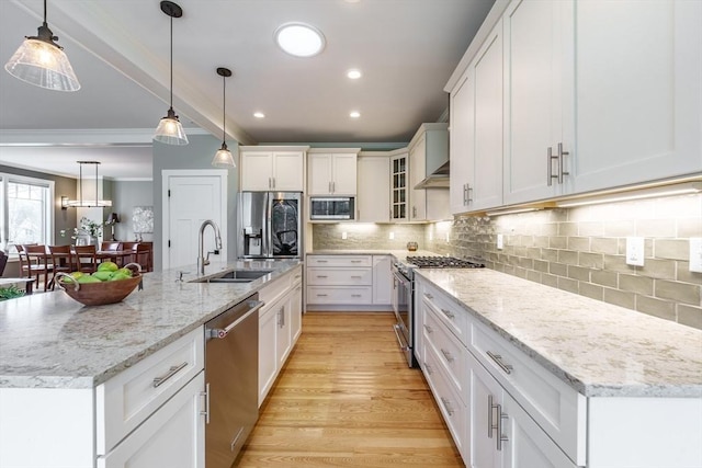 kitchen featuring decorative backsplash, appliances with stainless steel finishes, a sink, white cabinets, and ornamental molding