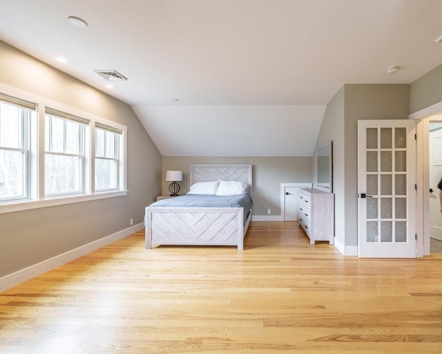bedroom with visible vents, baseboards, light wood-style flooring, and lofted ceiling