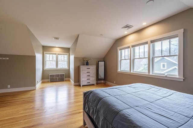 bedroom featuring baseboards, visible vents, lofted ceiling, and light wood-type flooring