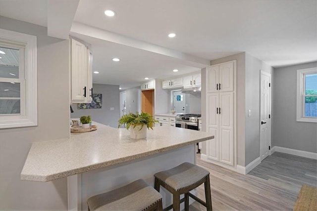 11 Rose Ave, Westport, MA 02790 - kitchen featuring a peninsula, a breakfast bar area, white cabinets, light wood-style flooring, and gas range
